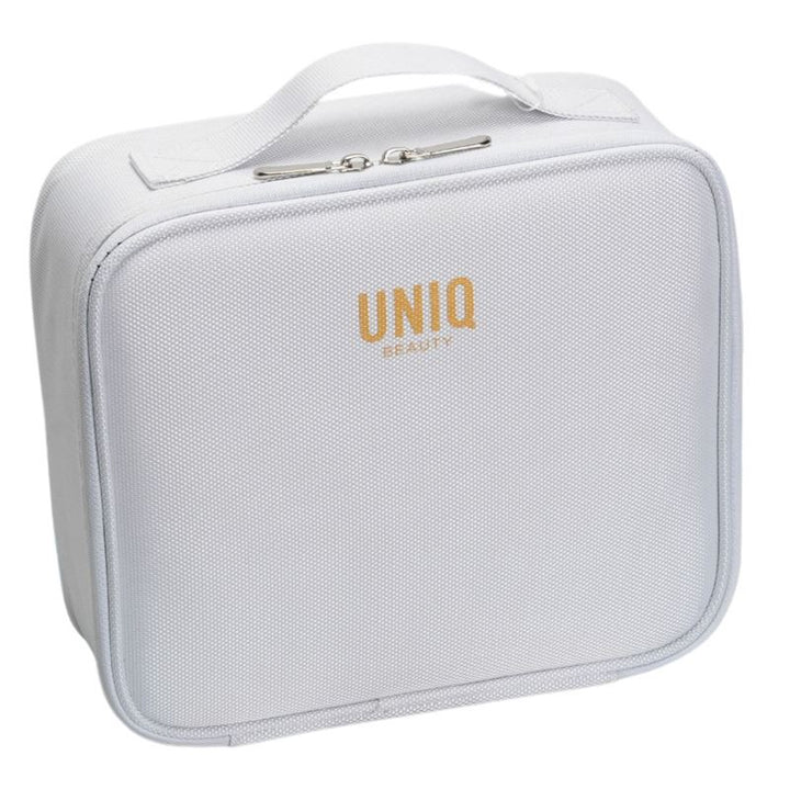 The UNIQ makeup travel bag is a white rectangular cosmetic bag with a top handle, gold UNIQ branding, and adjustable compartments for versatile storage.