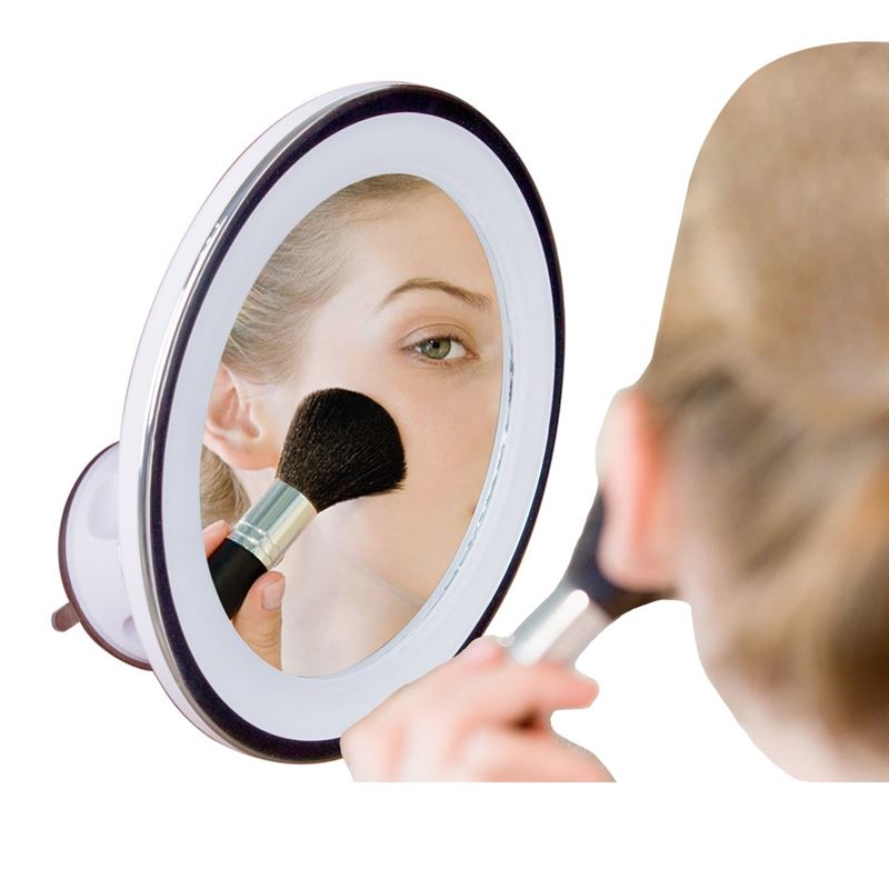 Using the UNIQ PRO BEAUTY Bathroom Mirror with LED Light and Suction Cup x10 Magnifying Mirror in white, a person applies powder to their cheek, taking advantage of the reflection’s clarity and powerful magnification.