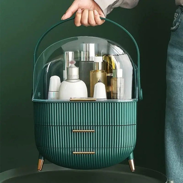 A hand holds the UNIQ Retro Makeup Box Organiser in Dark Mint/Dark Green by UNIQ, a portable cosmetic organiser with short legs, storing various bottles and containers, set against a dark green background.