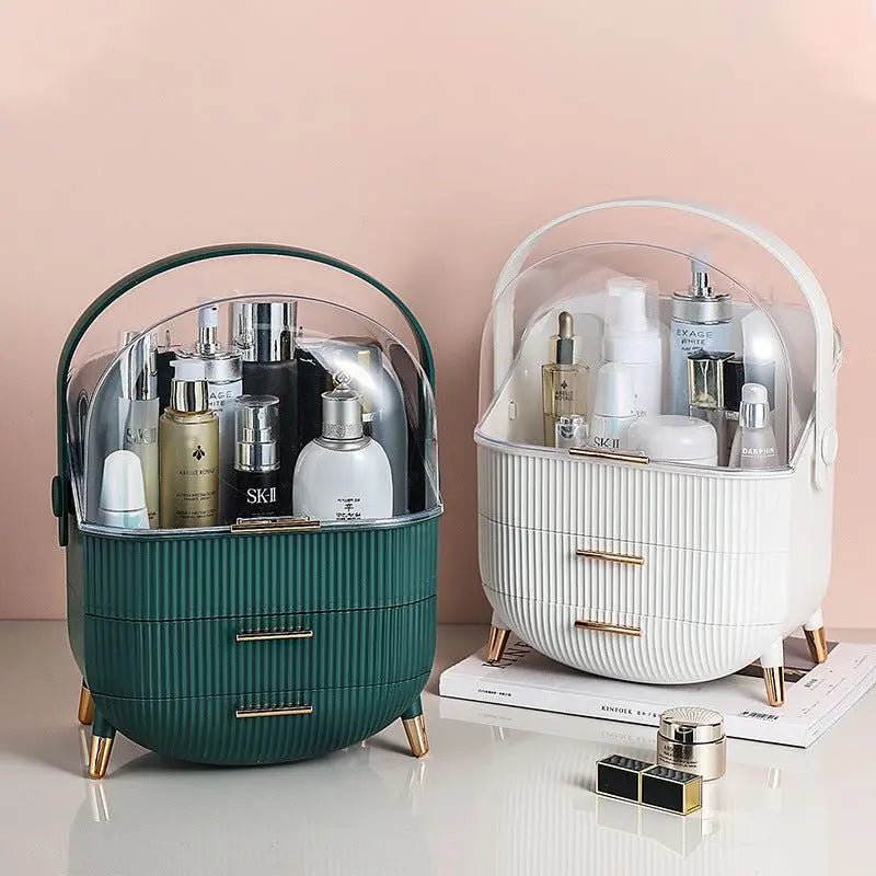 Two UNIQ Retro Makeup Box Organisers—one in Dark Mint, one in Dark Green—stand on gold legs with clear lids and drawers, neatly holding skincare and beauty essentials against a pink wall.