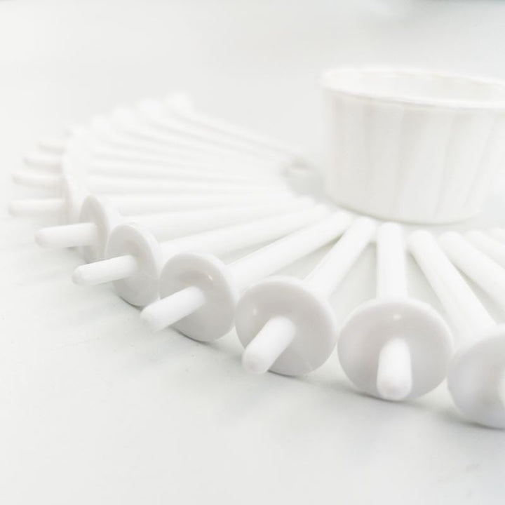 A close-up of several UNIQ Nose Wax Kit white applicator sticks with flat round ends, arranged semi-circularly with a small cup behind them, all on a white surface. Brand: UNIQ.